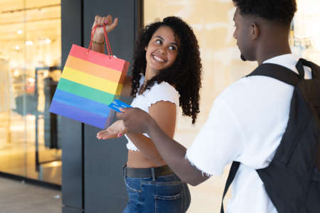 Man giving credit card to woman for purchase. Girlfriend is very happy for credit card. Buying clothes and fashion concept in urban contest.の写真素材