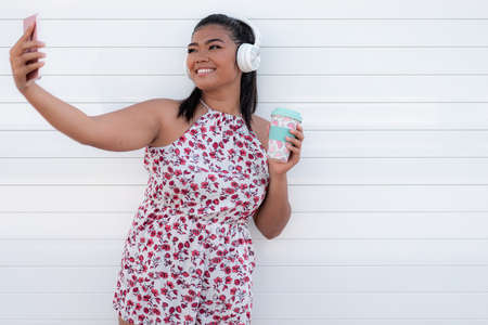 Young asian woman using smartphone for selfie and listening music. Technology concept.の写真素材