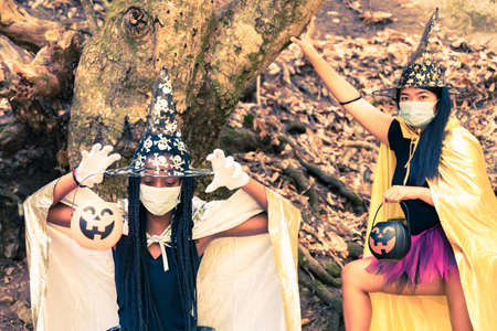 Two young women in witch halloween costumes with protective mask. Girls are playing trick or treat...