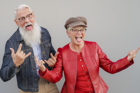 Full length portrait of a cheerful mature couple joking over gray wall. Happiness feeling in a recently retired couple. healthy life and lifestyle concept.の写真素材