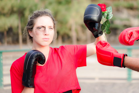 Domestic violence. Woman covering her face in fear of domestic violence. Man asking for forgiveness with a rose. Violence and protest concept.の写真素材