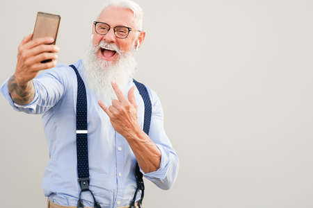 Portrait of attractive hipster man. Positive gray-haired pensioner making selfie. Technology and elderly concept.の写真素材
