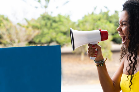 Funny young brunette woman girl screaming in megaphone. People sincere emotions lifestyle concept. Blue banner for copy space.の写真素材