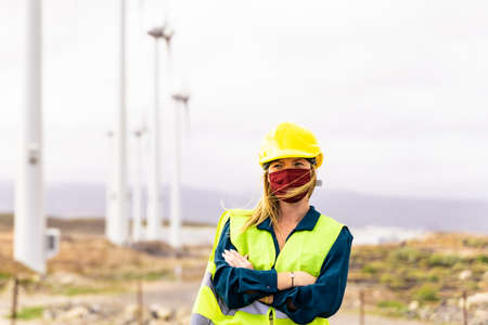 Front view of young woman engineer working in wind turbine farm. Clean energy, renewable energy and...