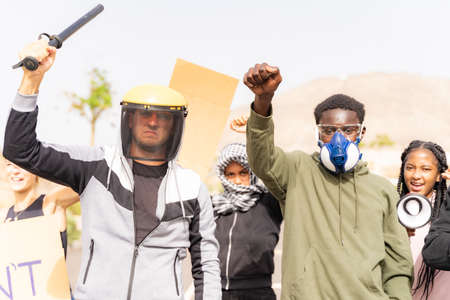 Multiethnic young people with raised fist shouting through megaphone and marched while being on anti-racism protest, coronavirus and no vax.の写真素材