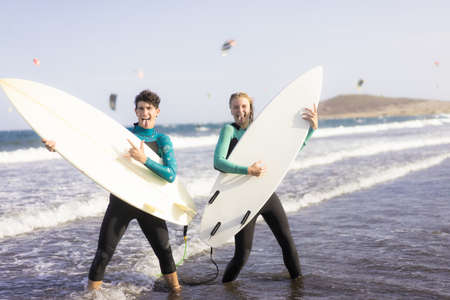 Full length portrait of a cheerful young couple joking. Rock people. Friends holding surfboards as...