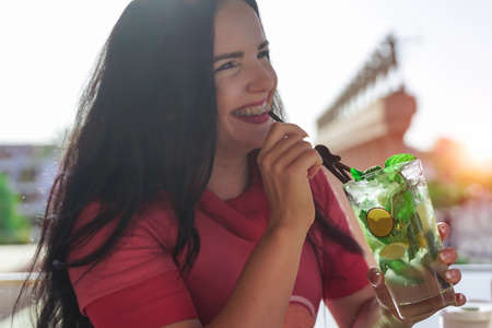 Close-up portrait of smiling teenage girl with braces drinking a mojito cocktail.の写真素材