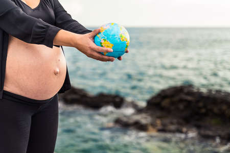 Pregnant Woman holding little globe earth. New life in the world and maternity concept.の写真素材