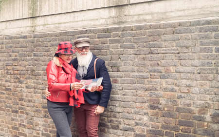 Senior couple with map and city guide on street. Pensioner reading tourist map London. Love and...