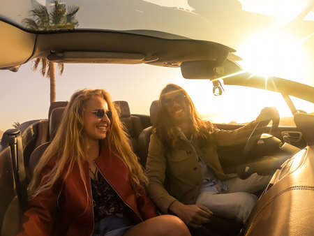 Romantic couple enjoying holidays driving a convertible car on the road at sunset. People rent car at vacations. Transport, people and lifestyle.の写真素材