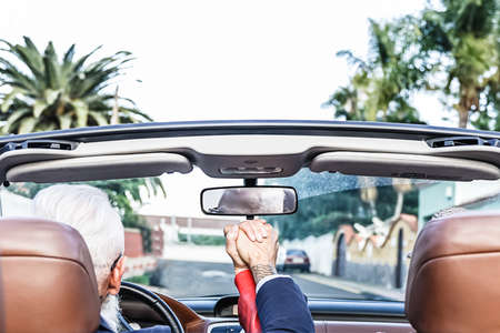 Happy romantic couple driving convertible car on the road. Happy senior couple having fun on new convertible car. Elderly lifestyle and travel transportation conceptの写真素材