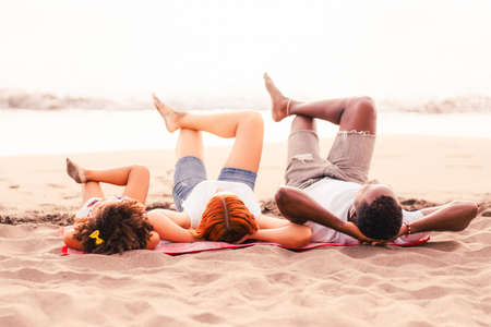 Young mixed race family relax on the beach. Parents with daughter enjoying a holiday at the sea. Family and travel concept.の写真素材