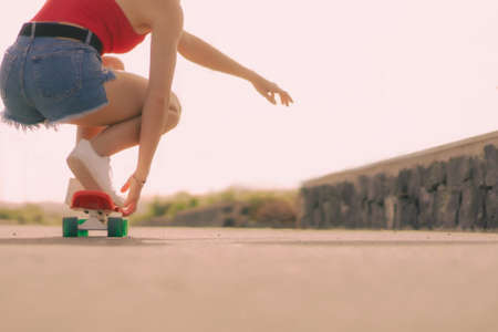 Closeup of young woman on skateboard in the skate park. Sport and lifestyle concept. Focus on foot and red longboard.の写真素材