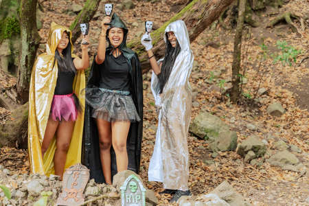 Happy Halloween! Three young women in diferent witch costumes on party on forest background.の写真素材