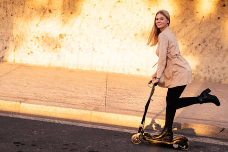 Young female commuter riding electric push scooter. New eco-friendly modern public city transport....