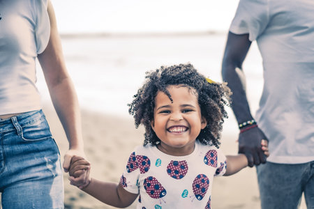 Young couple and their daughter strolling and enjoying a day at the beach. Close-up of the child. Concept of summer, holidays and family.の写真素材