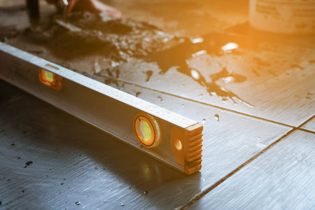 Ceramic Tiles. Tiler placing ceramic wall tile in position over adhesive with lash tile leveling systemの写真素材