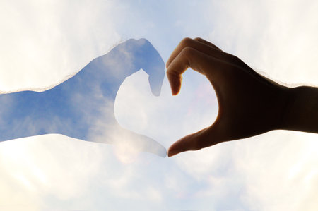 man hands forming a heart over the skyの写真素材