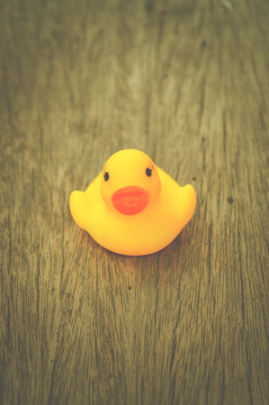 yellow plastic duck doll on wood floorの写真素材