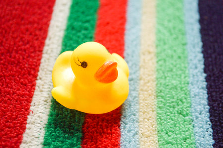 yellow plastic duck doll on colorful fabricの写真素材