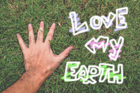 hand and word love my earth on green grassの写真素材