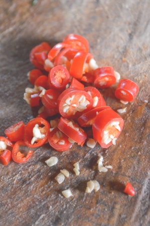 Slices of red chili peppers on wooden cutting boardの写真素材