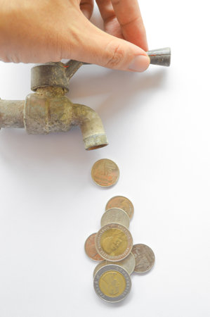 coin money flow out form steel faucet on white backgroundの写真素材