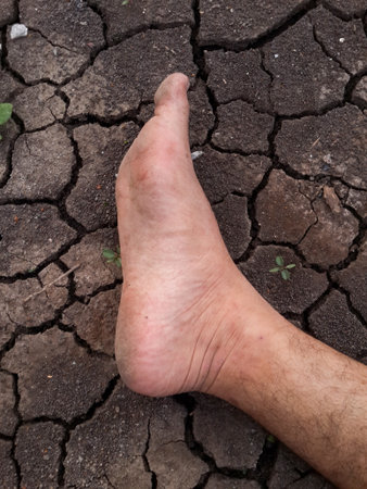 close up foot on crack soil in dry seasonの写真素材