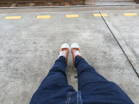close up man leg sitting near railway at train station