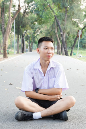 cute thai student in uniform sitting on road floorの写真素材