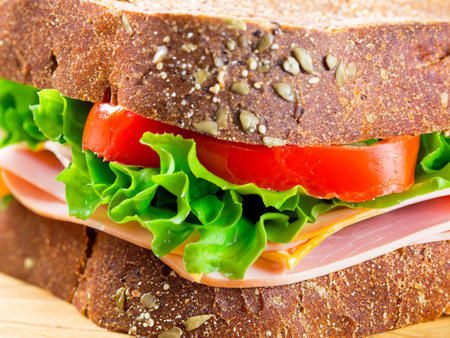 Delicious stuffed layer of ham and veggies in brown bread sandwichの素材