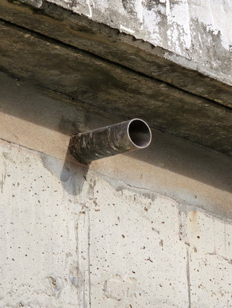 old pipe on the cement wall of the cement bridge