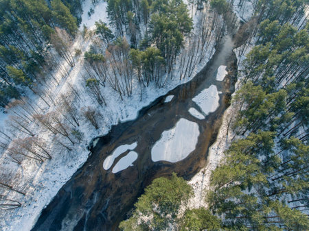 Top down view over snowy river valley with partially frozen river. Winter season in Lithuania.の写真素材