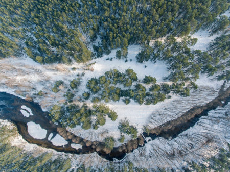 Top down view over snowy river valley with partially frozen river. Winter season in Lithuania.