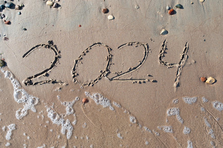 Hand written in sand on a beautiful beach. Textured sand with footprints and water.の写真素材