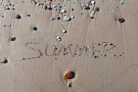 The word summer is written on the yellow sand of the beach. Blue wave and surf. Resort and vacation. Summer on the seaside. Relaxation rest concept.の写真素材