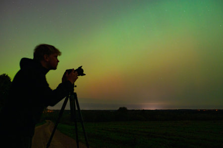 World Photography Day. Photographer with his camera and tripod taking pictures of Northern Lights....