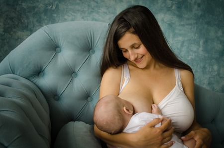 Breatfeeding baby. Mother nursing her child. Newborn eat breast milk in room.