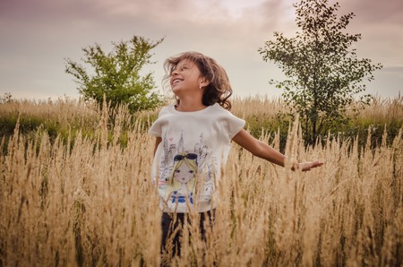 Girl jumping outside in the cornfield. Happy childhoodの写真素材