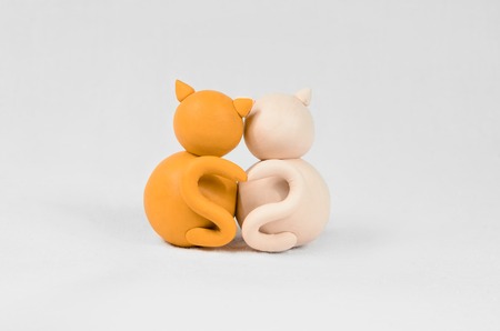 Two minimalistic animal figures in love. Lovely cat plasticine models having tails in heart shape isolated on white grey background. Happy Valentines Day in minimalism style.の写真素材