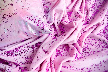 purple confetti sprinkled on pink velvet and a pillowの写真素材