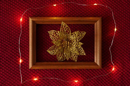 Christmas background. Gold sequined Christmas toys, a wooden frame and a garland lying on a red...