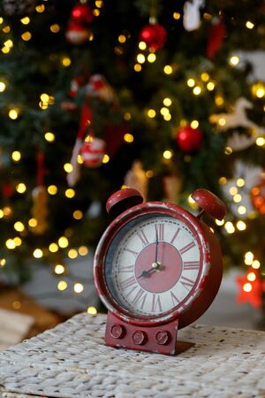 Christmas toy clock on the background of yellow lights of the garland, closeup