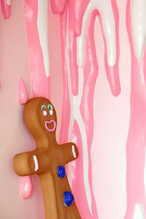 gingerbread man against the background of a wall covered with drips of white and pink glaze