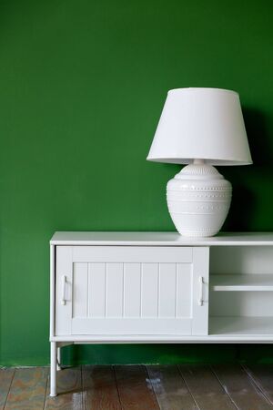 white lamp on a white pedestal against a painted green wallの写真素材