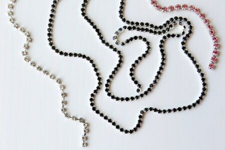 Chain of black, transparent and pink crystals on a white wooden background