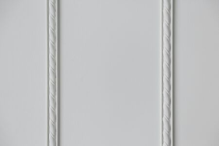 two strips of embossed stucco molding on a white wall, close up