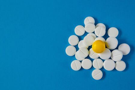 medicine and health, a slide of white and yellow pills on a blue background from aboveの写真素材