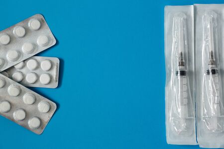 medicine, pills and syringe in a blister on a blue background side view