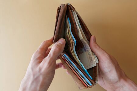Wallet with money in the hands of a man on a light monophonic background. Banknotes in the wallet....